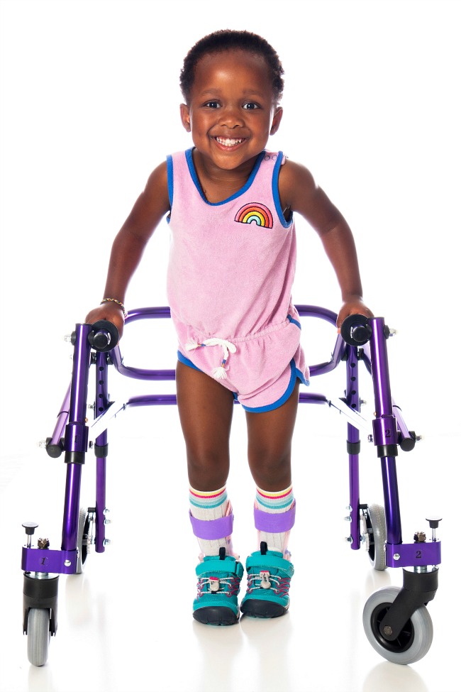 Young girl wearing AFOS with shoes in a walker.
